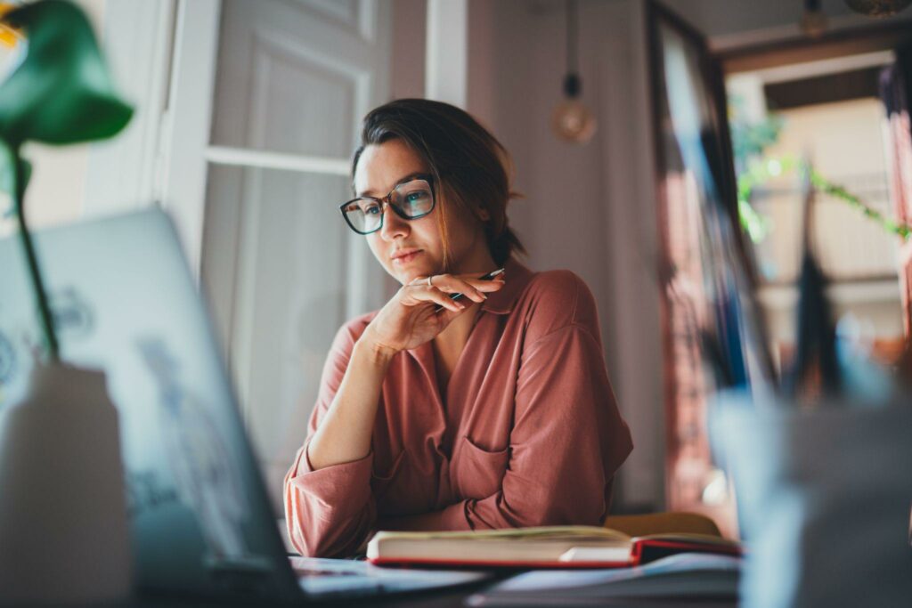 Beautiful businesswoman sitting at table opposite laptop in workplace brainstorming new project