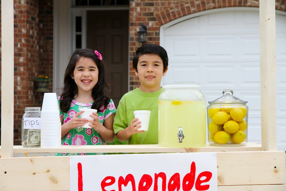Children selling lemonade in front of their home