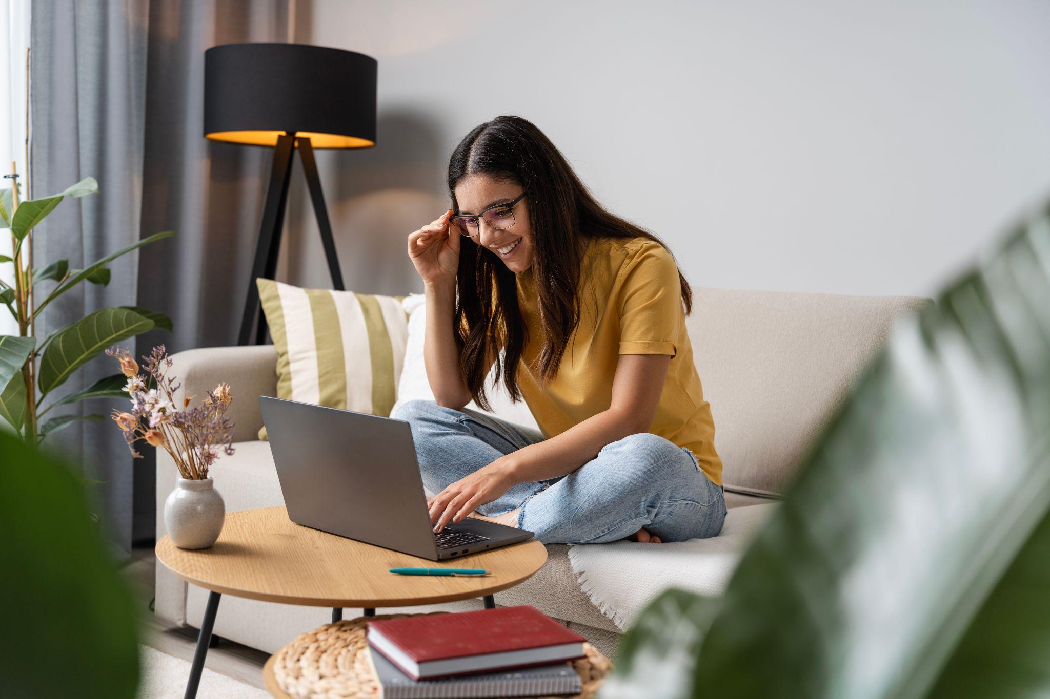 Happy student doing her work at home on laptop in a cosy room