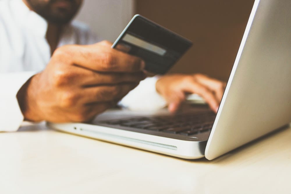 Man's Hands Holding A Credit Card And Using Laptop For Online Shopping