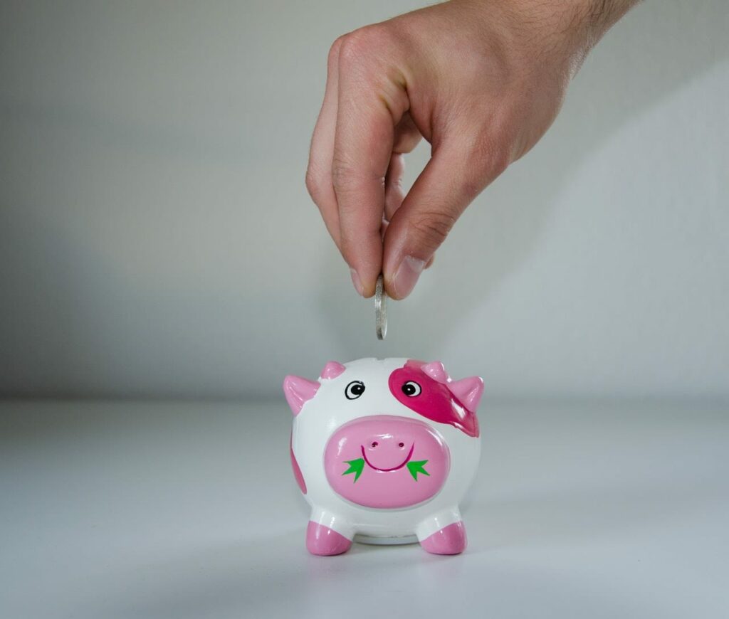A hand putting an one euro cent into Piggy bank