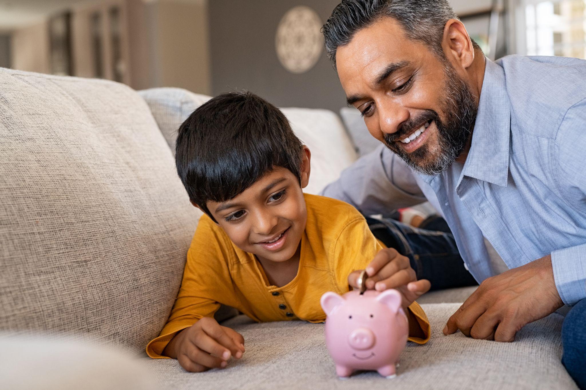 Man teaching his child how to save money in a piggy bank