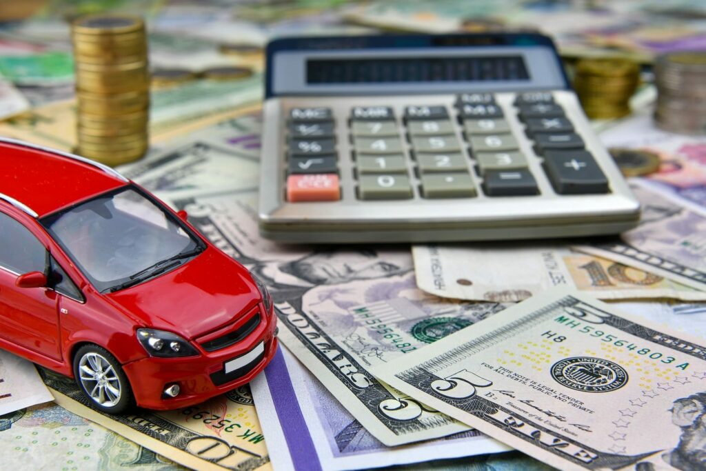 Calculator and red toy car on a variety of national currency banknotes