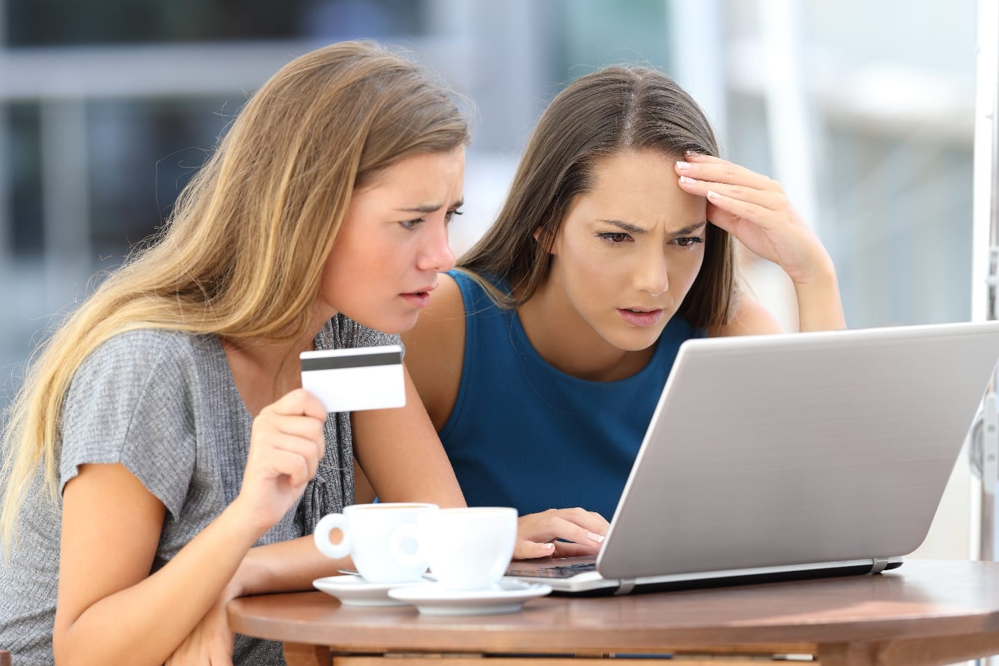 Two worried women having problems buying online with a laptop and credit card