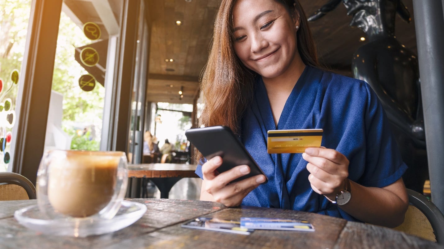 asian woman using credit card for purchasing and shopping online on mobile phone