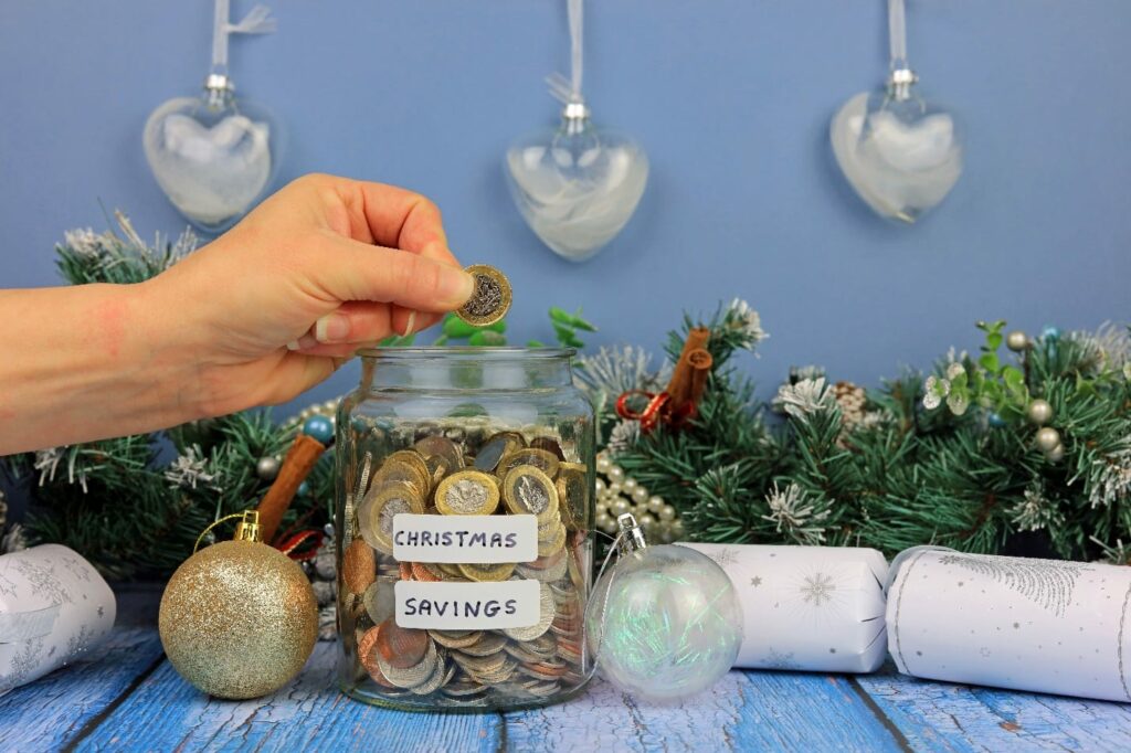 Hand put coin in glass jar, saving money for Christmas