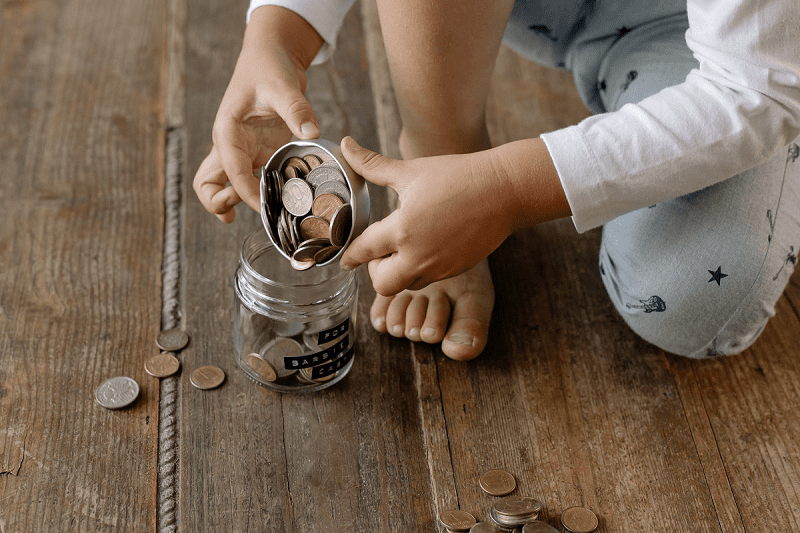 Child hand putting coin into glass