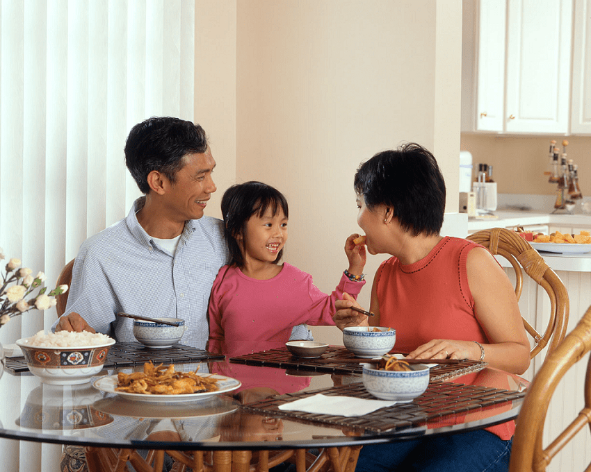 An Asian family seated around a table and eating