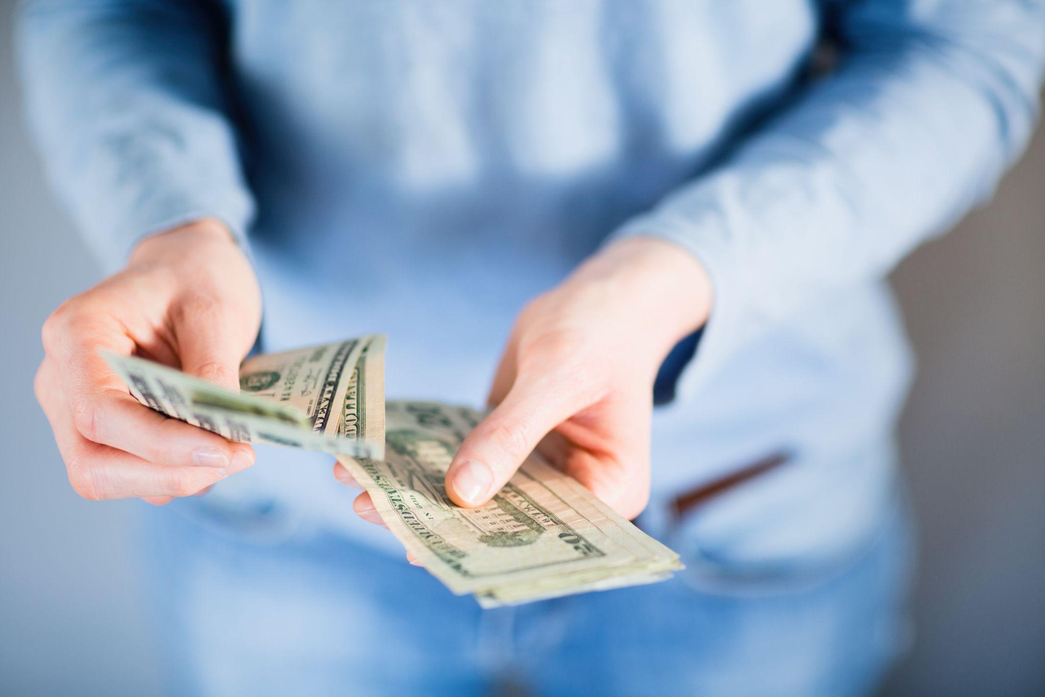 Female hands counting US Dollar bills or paying in cash