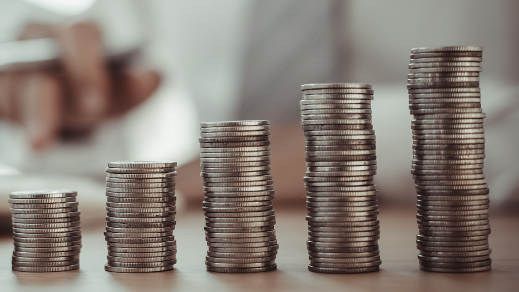 Money saving concept. Close up of stack of silver coins on wooden table.