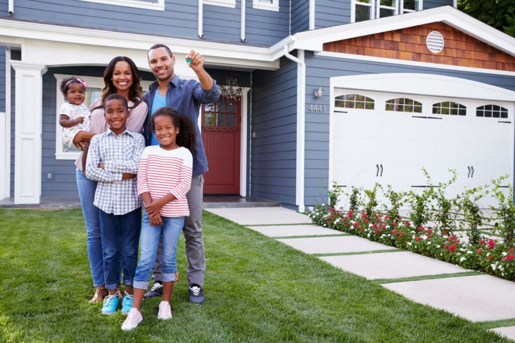 family posing in front of their new house