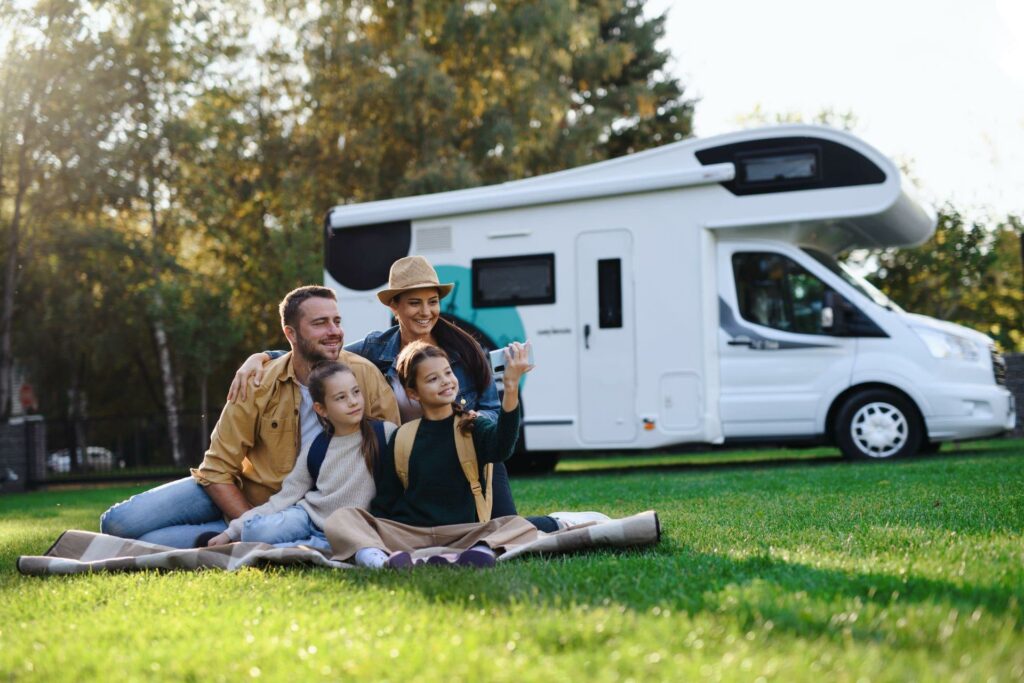 Happy young family with taking selfie with caravan at background outdoors.