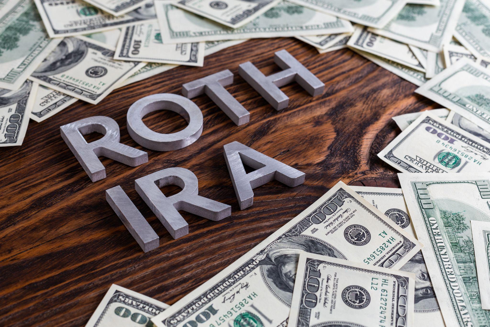 words ROTH IRA laid on wooden surface with us dollar banknotes