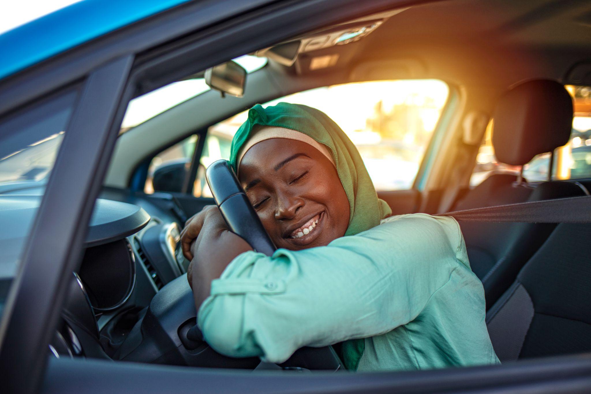 Beautiful woman is hugging her new car and smiling