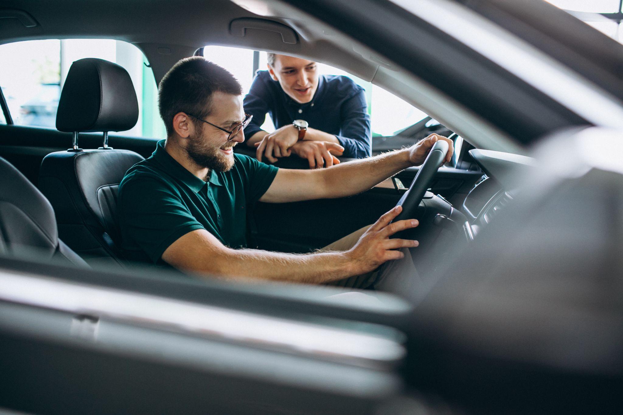 Young man testing new car at a showroom