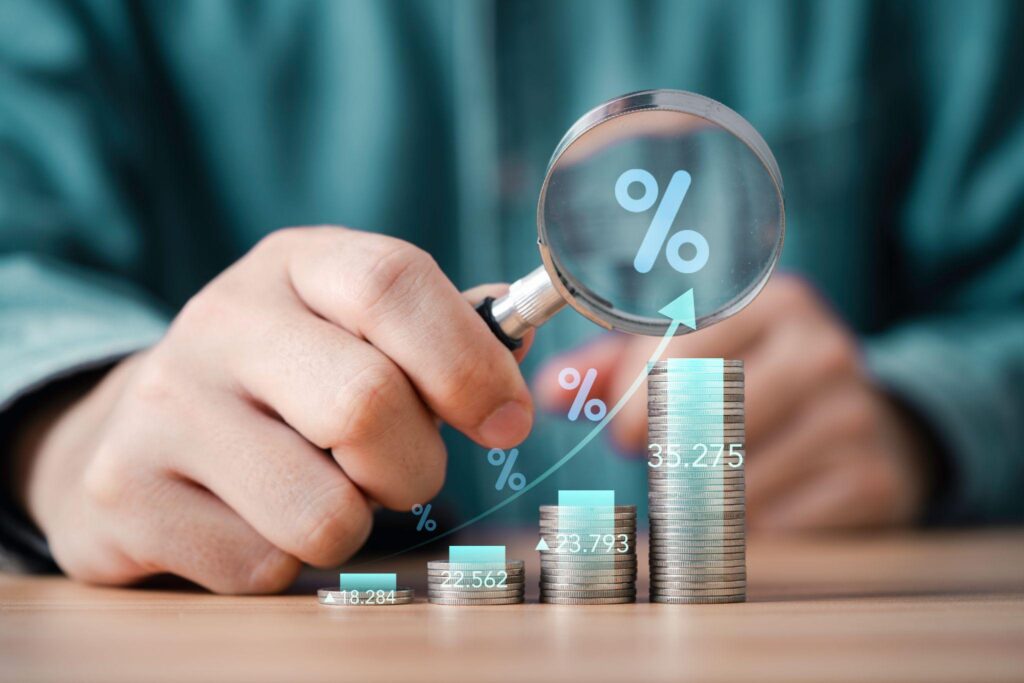 Businessman use magnifier glass focus to increasing coins money with percentage for analysis financial banking increase interest rate