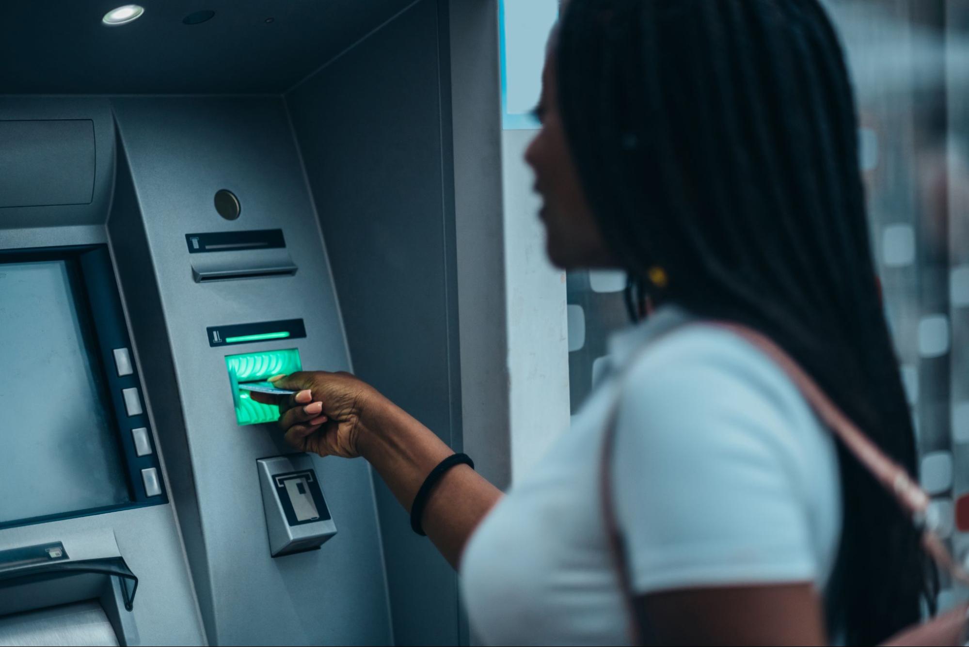 A woman putting her card into an ATM